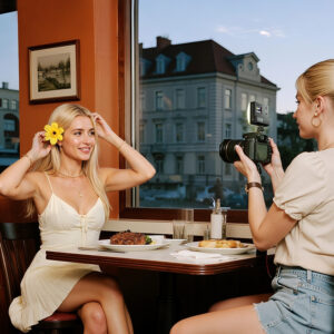 Content creator filming woman in restaurant using Ulanzi C10RGB LED video light with adjustable RGB for indoor lighting