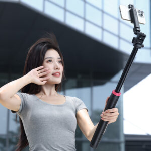 Woman using Ulanzi MT-78 as selfie stick outdoors with smartphone mounted on ball head, legs folded for portable handheld use